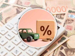 un dado con il simbolo della percentuale, un'auto in miniatura, una tastiera con vicino banconote