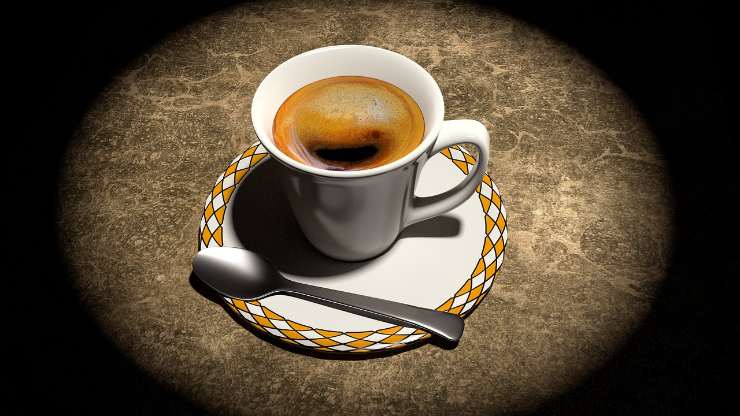 una tazzina di caffè con cucchiaino vicino