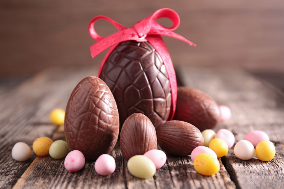 Primo piano di uova di cioccolato di varie dimensioni su tavolo di legno