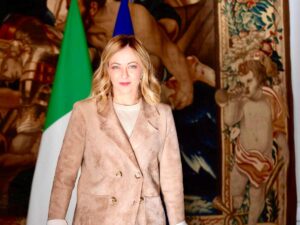 Giorgia Meloni in posa dinanzi alla bandiera italiana ed europea