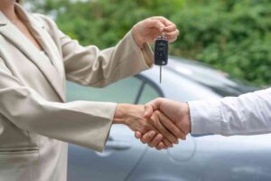 una stretta di mano con sopra una chiave per auto