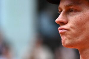 Primo piano di Jannik Sinner con espressione ambigua