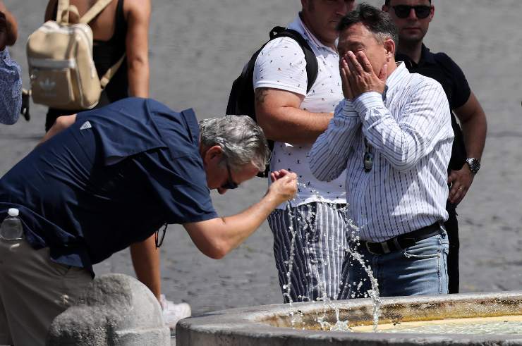persone si rinfrescano con l'acqua di una fontana