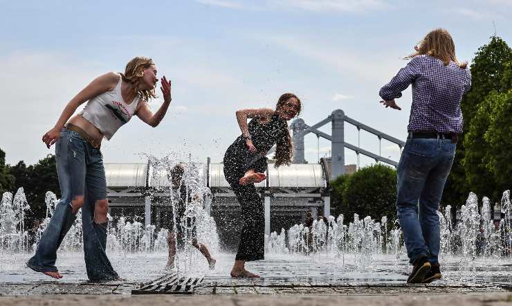 ragazze si rinfrescano con l'acqua di una fontana
