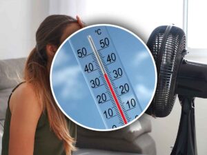termometro con dietro una persona che si rinfresca al ventilatore