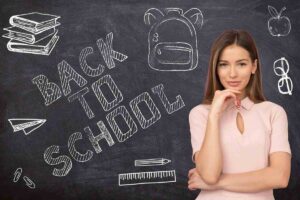 una ragazza davanti a una lavagna con scritta Back to School