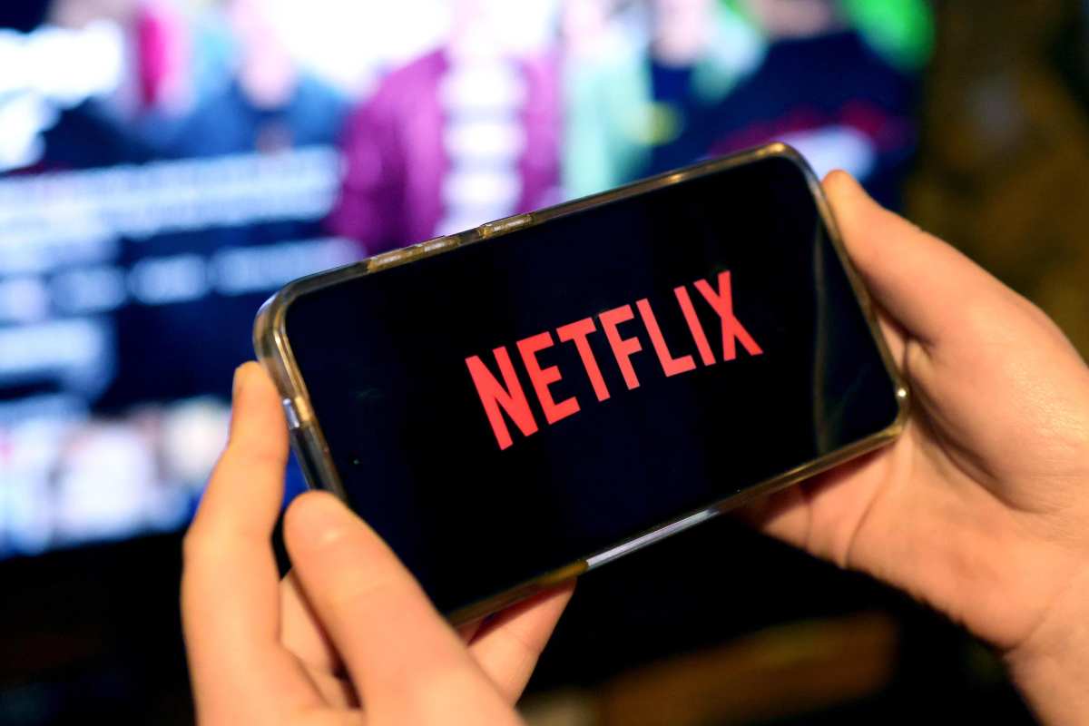 smartphone tra le mani con logo Netflix