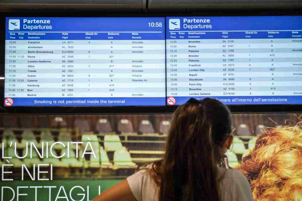 Persona davanti ad una schermata dei voli in partenza (quasi tutti annullati)