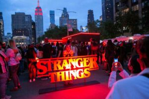 Una fan dietro al logo di Stranger Things tra i palazzi