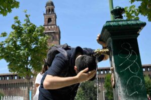 Una persona cerca refrigerio dall'intenso caldo bagnandosi il volto con dell'acqua da una fontanella di piazza Castello