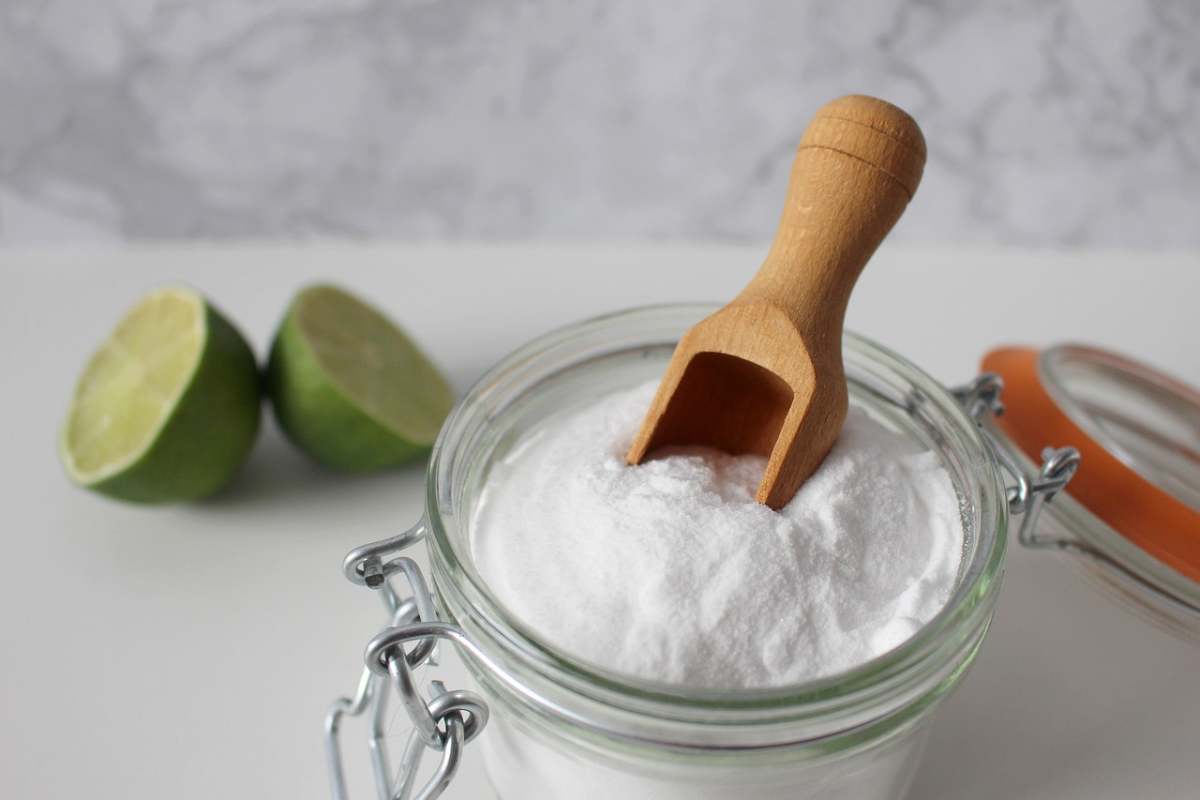 un contenitore con il bicarbonato e dietro un limone spaccato a metà