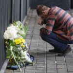 Persona commossa in ginocchio vicino ad un mazzo di fiori