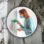 muro con la muffa e una donna con mascherina e spruzzino