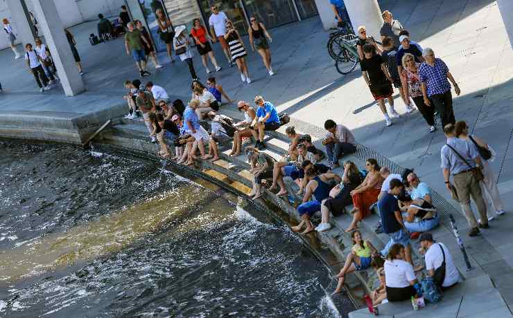 persone si rinfrescano con l'acqua di una fontana