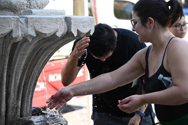 due persone si rinfrescano con l'acqua di una fontana