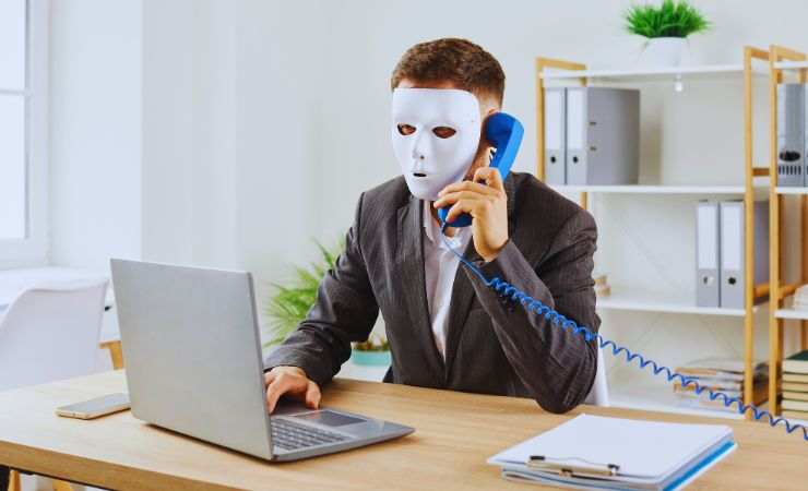truffatore con maschera al telefono e al pc
