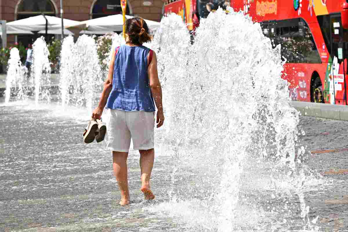Una persona cerca refrigerio camminando scalza presso una fontana