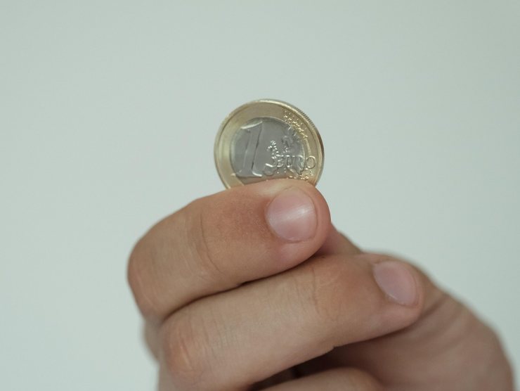Moneta da un euro tra le dita di una persona