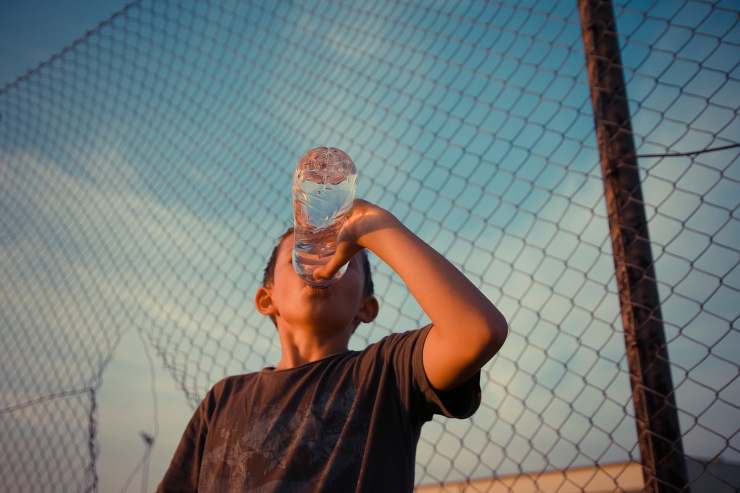 Ragazzo beve acqua dalla bottiglia