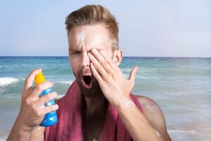 un ragazzo si spalma la crema solare sul viso