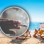 una sigaretta accesa con dietro due sdraio in spiaggia