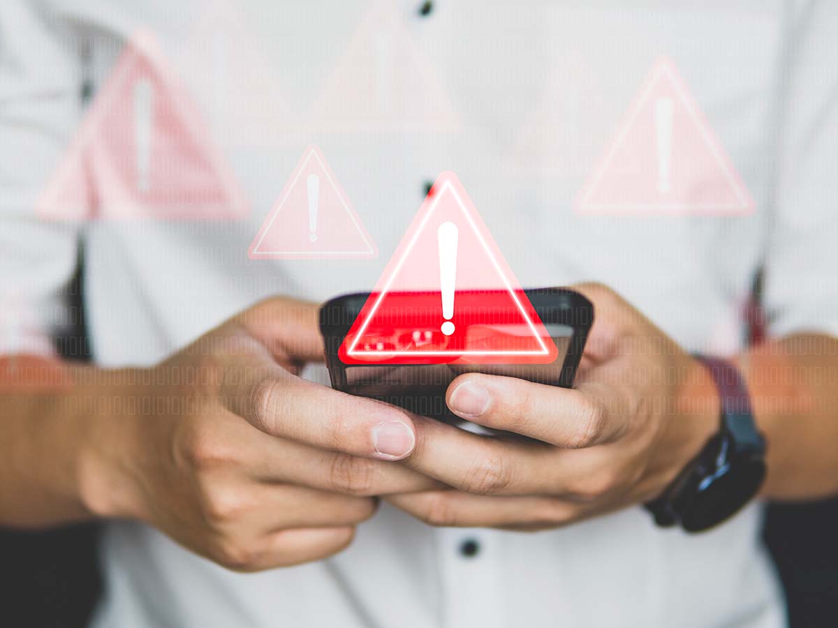 triangolo segno pericolo con dietro una persona con smartphone