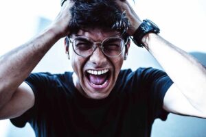 un uomo che urla con le mani sui capelli