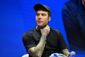 Fedez seduto con una mano sul collo durante un congresso di Forza Italia
