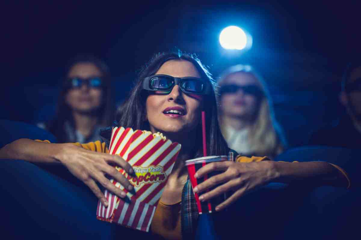 ragazza con cestino di pop corn in una sala cinema guarda un film
