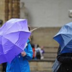 Persone si riparano a fatica dalla pioggia con un ombrello