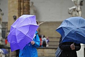 Persone si riparano a fatica dalla pioggia con un ombrello