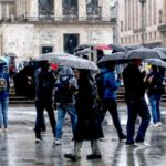 Gente passeggia con ombrello mentre piove