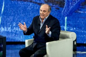 Gerry Scotti parla seduto in poltrona