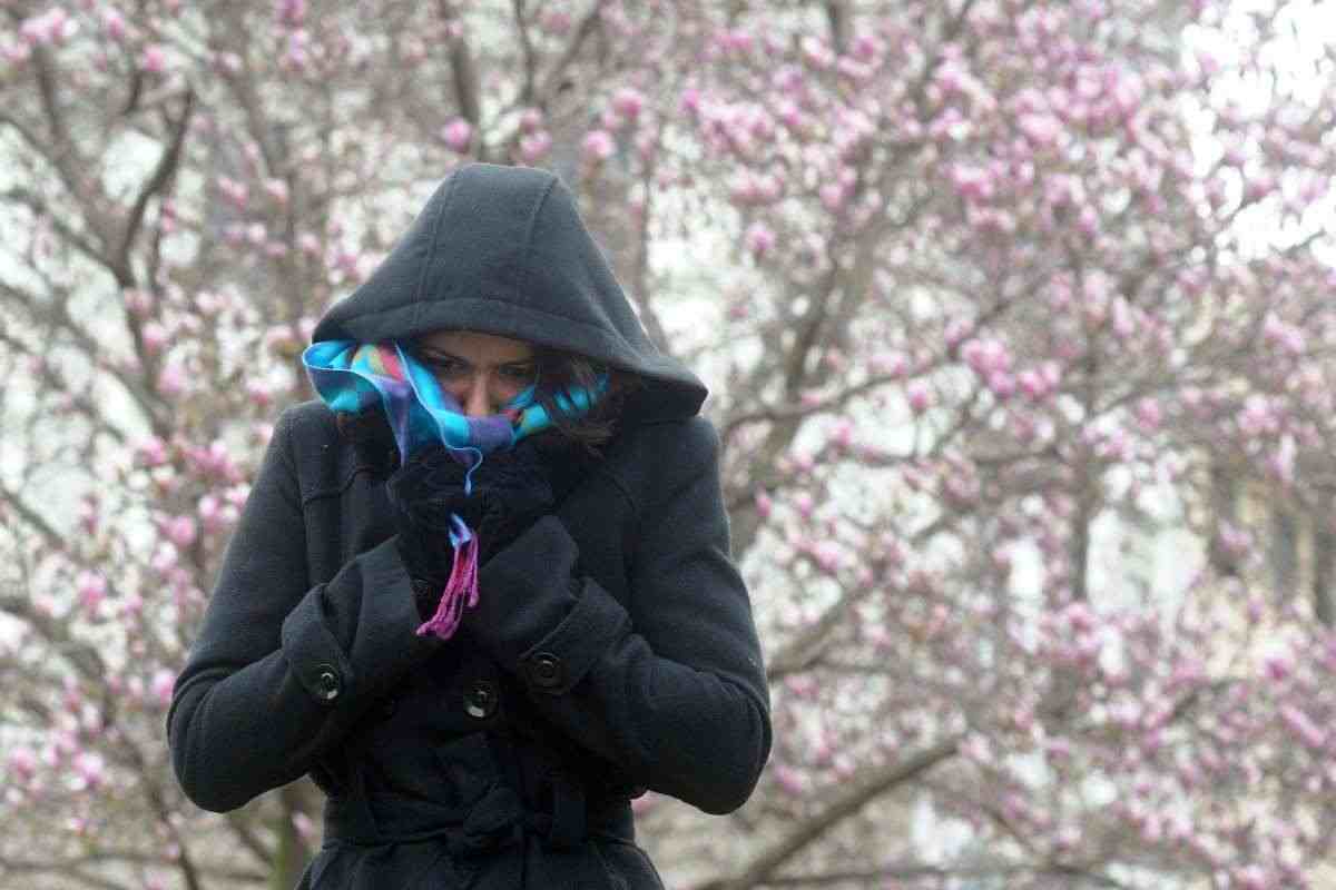 Una donna si ripara dal freddo indossando un giubbino imbottito con cappuccio