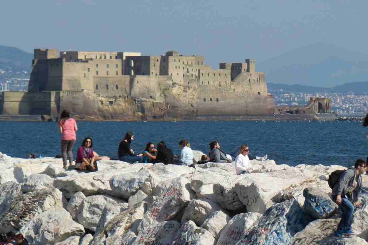 Persone che prendono il sole sugli scogli presso il Golfo di Napoli