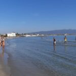 Persone in spiaggia che passeggiano o fanno il bagno
