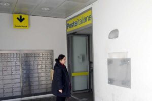 Una signora si appresta ad entrare in una sede di Poste Italiane
