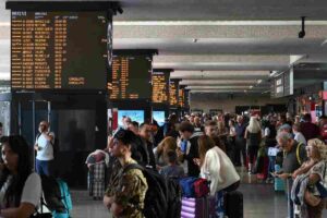 Persone che passeggiano in stazione osservando i monitor di servizio