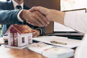 due mani che si stringono e sotto un modellino di una casa
