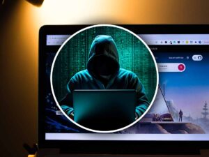 nel cerchio un uomo incappucciato con dietro un computer