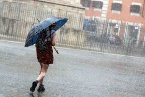 Donna in strada con ombrello sotto la pioggia