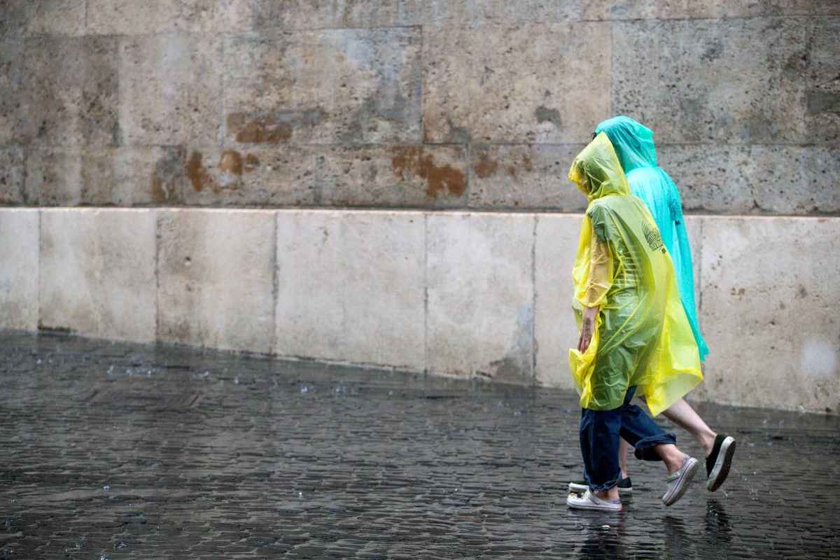 Persone camminano in strada sotto la pioggia 