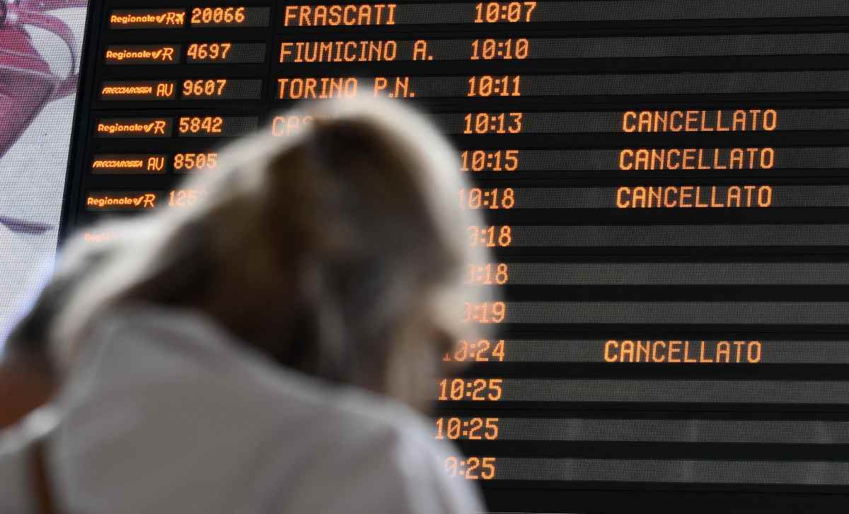 Signora in stazione davanti a schermo orari