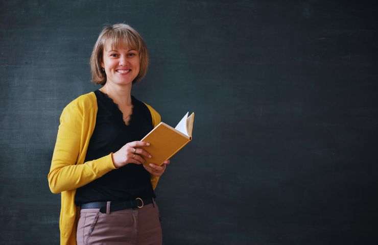 insegnante con libro alla lavagna